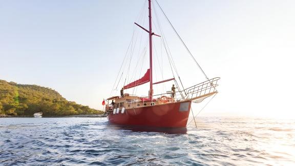 Le gulet Le Rouge glisse sur l'eau au lever du soleil, prêt pour une nouvelle aventure.