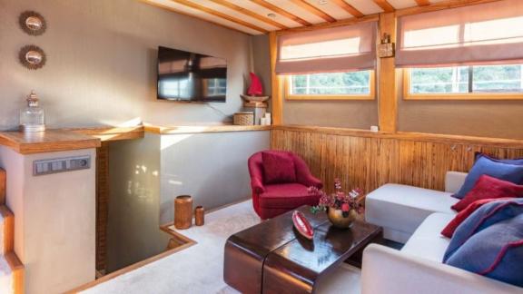 Bright living area with a cozy seating corner, flat-screen TV, and stylish decor on a yacht.