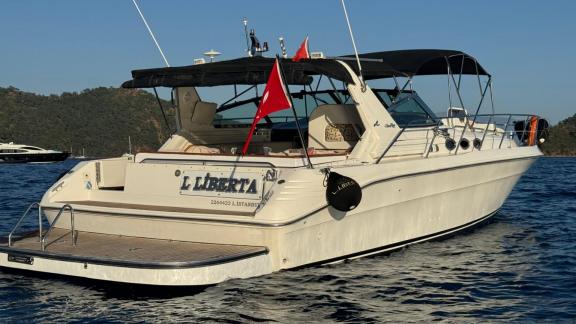 Motor yacht Liberta, anchored in a bay, rear view.