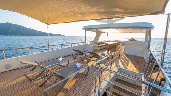 The spacious sun deck of the luxury trawler Lycian Dream in Fethiye offers comfortable loungers and shaded areas.