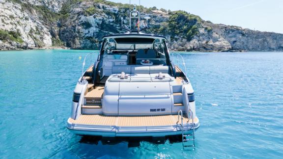 The aft deck of motor yacht Make My Day is comfortably positioned over turquoise waters, perfect for relaxation.