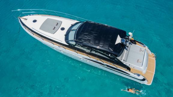 A person enjoys swimming next to motor yacht Make My Day in turquoise waters.