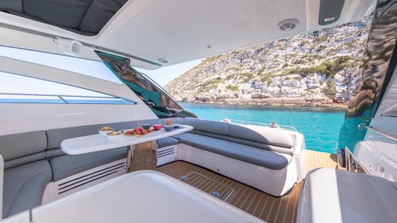 The aft deck of yacht Make My Day features a comfortable seating area with snacks on the table.