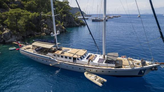 Elegant motorsailer with 5 cabins at anchor in an idyllic bay of Fethiye, surrounded by crystal clear water.