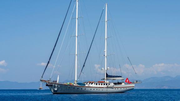 Stylish motor sailer with 5 cabins, anchored quietly in the waters of Fethiye, under clear skies and in front of picture