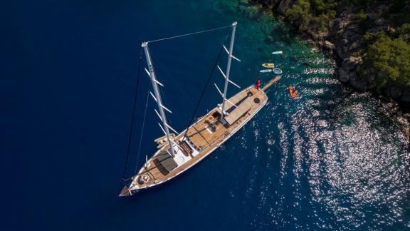 Motor sailer with 5 cabins, anchored in the turquoise-blue bay of Fethiye, surrounded by picturesque cliffs and pine tre