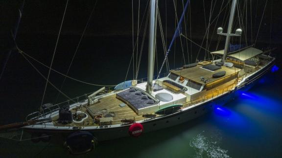 Elegant motorsailer with 5 cabins in Fethiye, illuminated at night and anchored in calm waters.