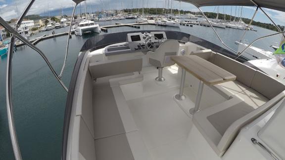 The upper deck of the motor yacht Ocean Dreamer in the harbor features a seating and helm area.