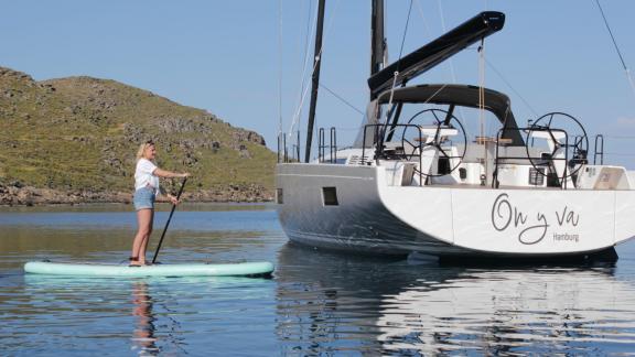 Eine Frau paddelt neben der vor Anker liegenden Luxusyacht On Y Va in Griechenland.