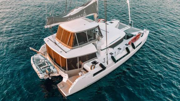 The Oneida 2 catamaran with its rear deck and dinghy, anchored in the water.