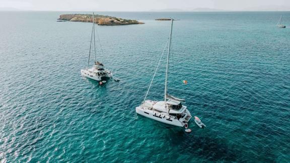 The Oneida 2 catamaran is seen anchored calmly near an island in a peaceful sea.