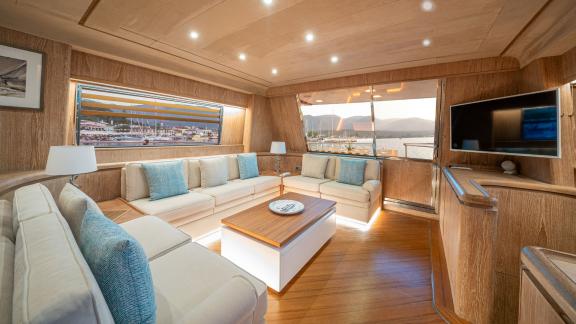 The spacious salon of Opera yacht features a comfortable seating area with large windows offering marina views.