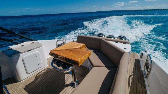 Bequemer Sitzbereich und Tisch auf dem Achterdeck der Orix-Motoryacht mit Meerblick.