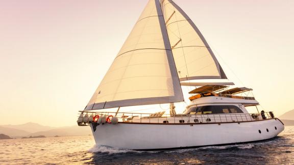 The sailing yacht Perdue glides through calm waters at sunset.