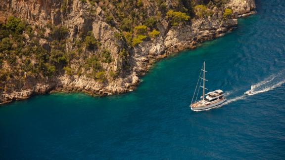 The yacht Perdue sails majestically along the impressive rocky coastline of Fethiye.