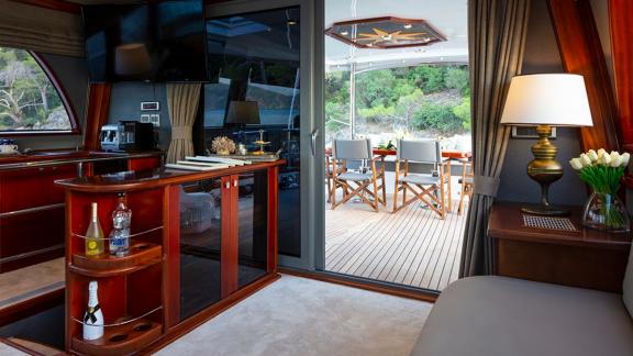 Elegant salon with a bar leading to the stylish dining area on the deck of the sailing yacht.