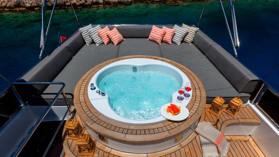 Relaxing hot tub on the deck of a sailing yacht, surrounded by cushions with a view of the sea.