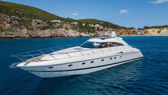 Princess Juliet is seen anchored in calm waters with the Ibiza coastline in the background.