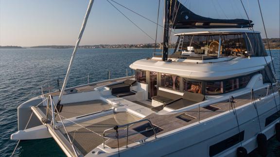 Among catamaran rental options in Kastela Princess Karla front deck with lounge areas is seen anchored in calm sea.