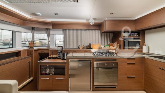 Fully equipped modern kitchen in the catamaran Princess S with wood decor and large windows