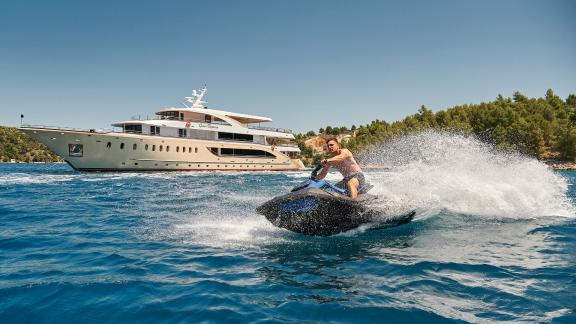 A guest enjoys a jet ski adventure next to the luxurious motor yacht Queen Eleganza in Croatia