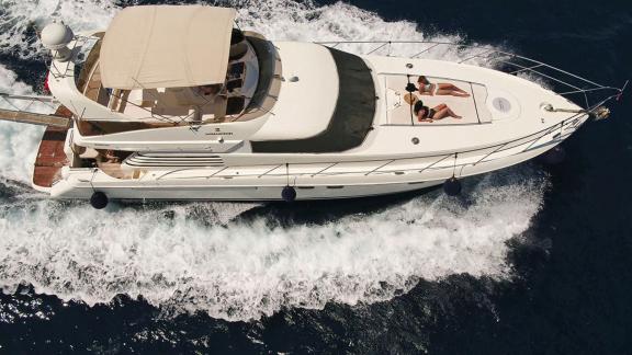 The motor yacht Queen speeding through the sea, with people sunbathing on deck.