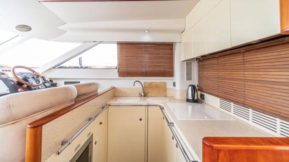 Modern kitchen of the motor yacht Queen with elegant white cabinets and a coffee maker.