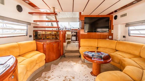 Stilvoller und komfortabler Wohnbereich der Motoryacht Queen mit gelben Sofas und großem Fernseher.