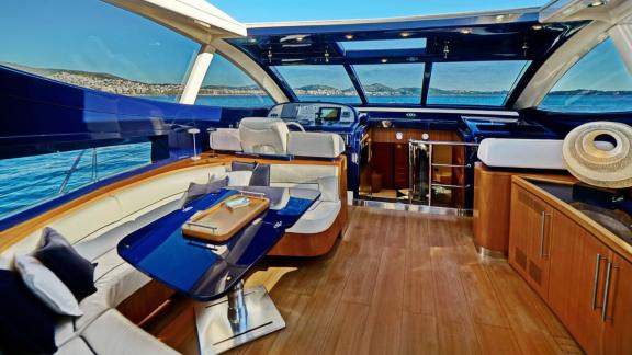 Im Salon der Sea U Motoryacht befinden sich ein blauer Glastisch, cremefarbene Sitze und vorne der Steuerstand.