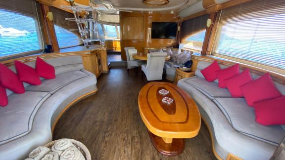 Spacious salon of motor yacht Ser 1 with large sofas, red cushions, and a wooden table.