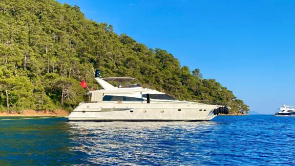 Motor yacht Ser 1 is anchored in a tranquil cove surrounded by forest.