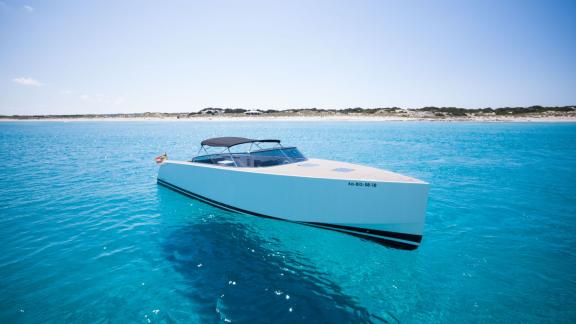 The Smart Ass motor yacht is seen from the front and side, floating in clear waters.