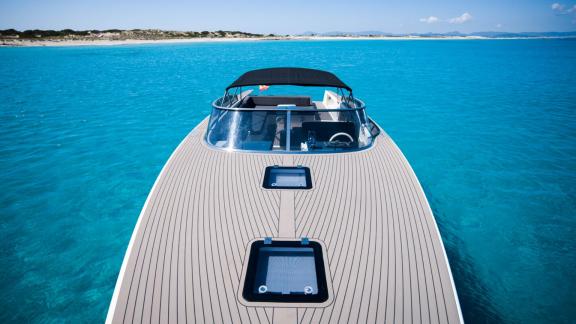 The sleek front deck of the Smart Ass motor yacht, seen over crystal-clear waters.