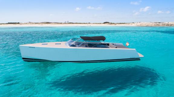 The Smart Ass motor yacht is seen from the side, floating in turquoise waters.