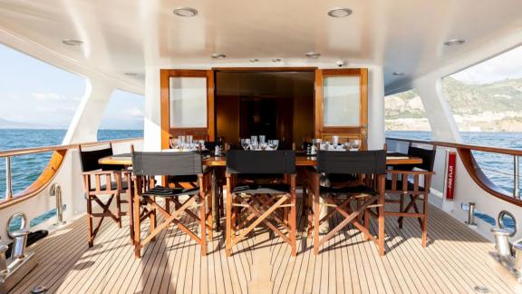 Among motor yacht rental options in Athens Sounion II aft deck dining table and seating area is seen onboard.
