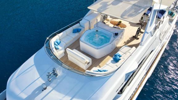 Großzügiges Deck mit Jacuzzi auf der Luxusyacht Stella Fiera, über türkisfarbenem Meer.