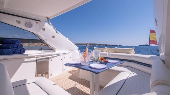 Ibiza açıklarında demirli Stress motoryatın arka güvertesinde deniz manzaralı yemek alanı yer alıyor.