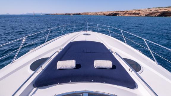 Ibiza koylarında demirli Stress motoryatın ön güvertesinde geniş bir güneşlenme minderi ve yastıklar yer alıyor.