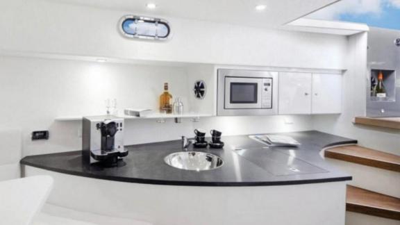 The modern kitchen of the Tequila motor yacht offers a sleek white design and coffee maker, providing a comfortable cook