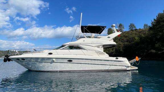 Motoryacht This Corner, vor Anker im blauen Wasser, Seitenansicht.