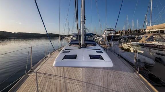 The spacious teak foredeck of the Tourbillon sailing yacht offers a peaceful view of the marina.