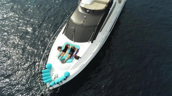 Among Nice yacht charter options Turquoise motor yacht shows bow with sunbeds for relaxing at sea.