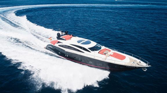 Motor yacht Um7 speeds through the blue sea, creating waves on the water's surface.