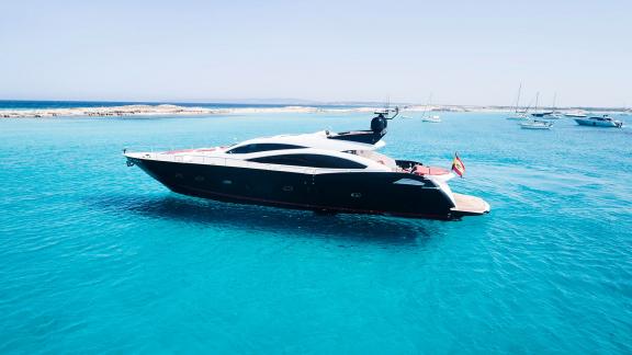 Motor yacht Um7 is calmly anchored in the middle of turquoise waters.