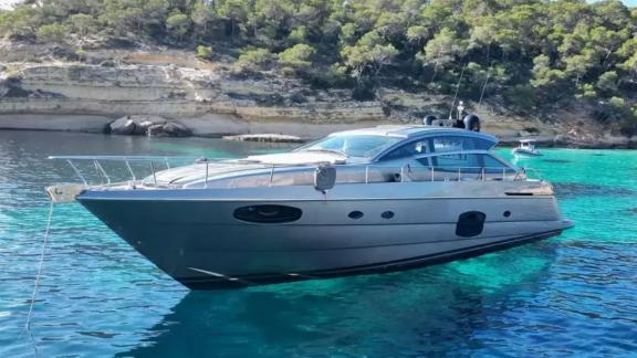 Motor yacht Urus anchored in a peaceful cove, showcasing its modern lines over turquoise waters.