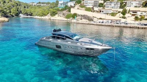 Motor yacht Urus anchored near the coast, floating on turquoise waters.