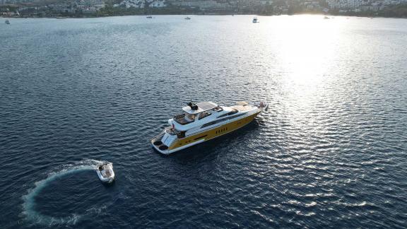 The Vedo B yacht glides over the vast blue waters, accompanied by a small boat, looking magnificent.