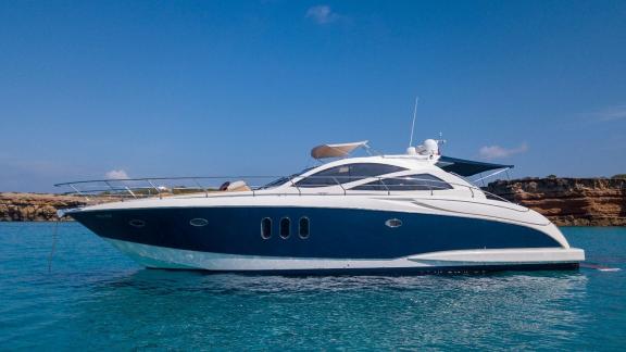 Motor yacht Vida Boa rests peacefully at anchor in turquoise waters, showcasing its elegant design.