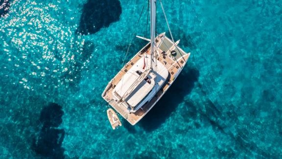 The White Caps catamaran is captured from an aerial view in crystal clear water.