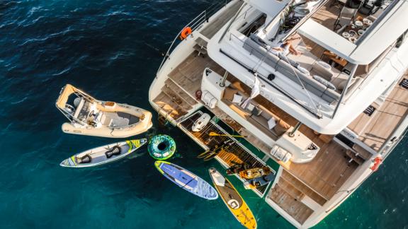 At the rear of the White Caps catamaran, there are various water toys and a tender boat.